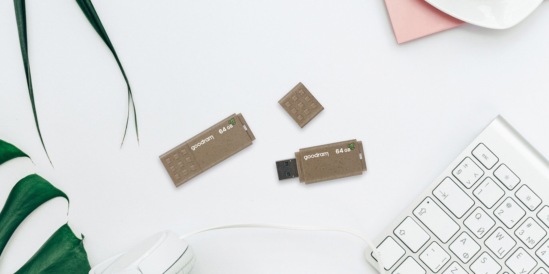 USB UME ECO FRIENDLY marki Goodram w otoczeniu kwiatów i klawiatury komputerowej